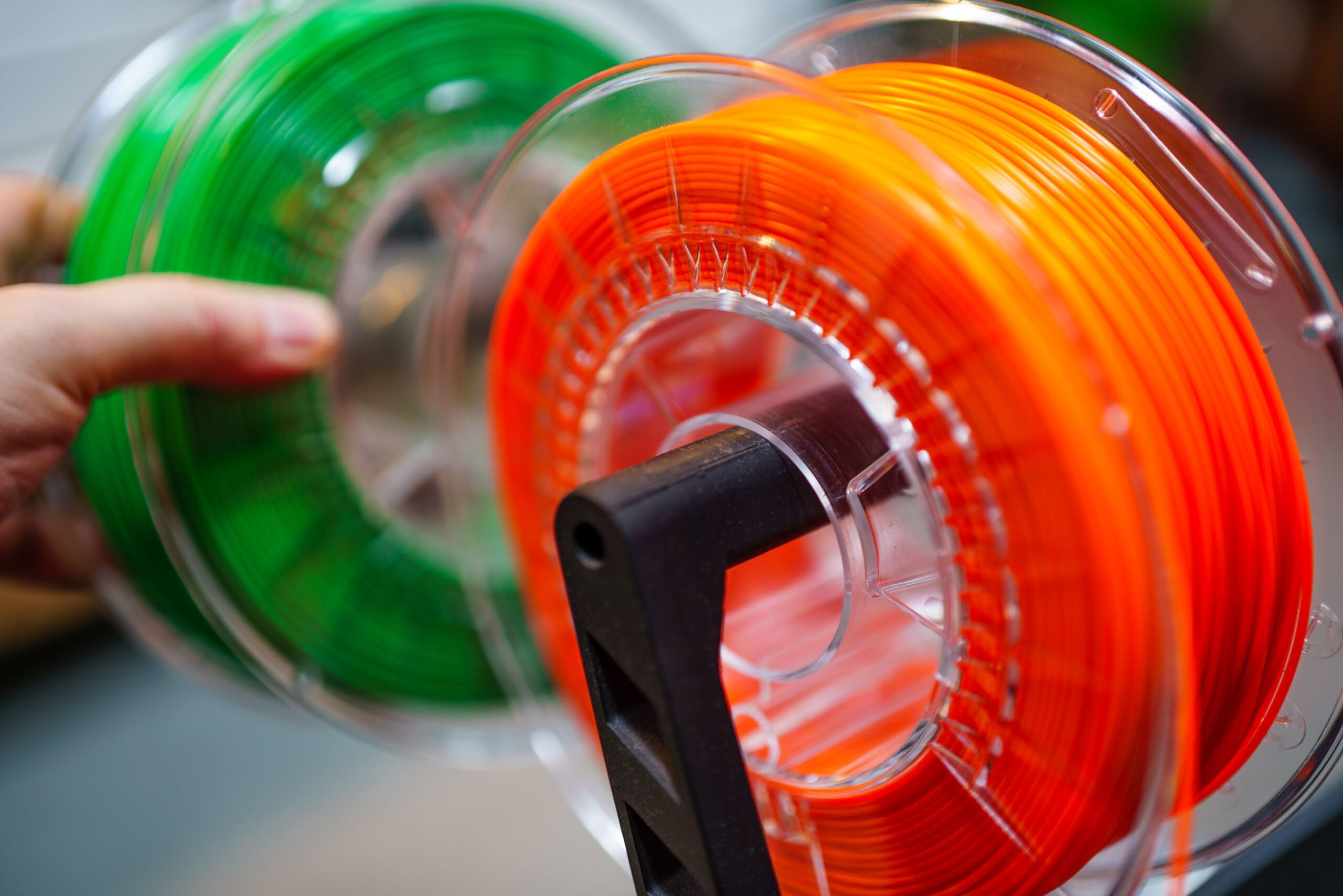 Home Vibrant orange and green 3D printer filament spools for innovative manufacturing uses.