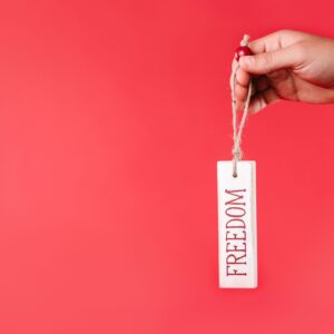 Home A hand holds a freedom tag on a red background, symbolizing independence and liberty.